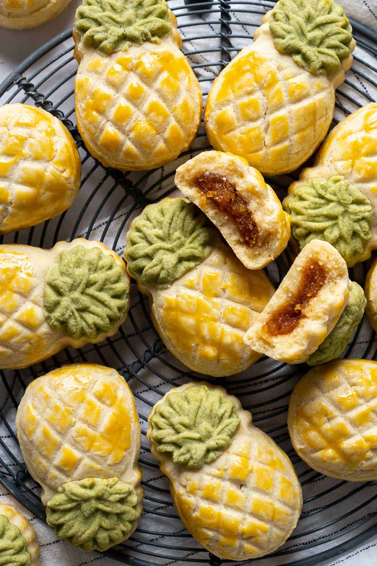 Pineapple tarts on a rack with one broken in two in the middle.