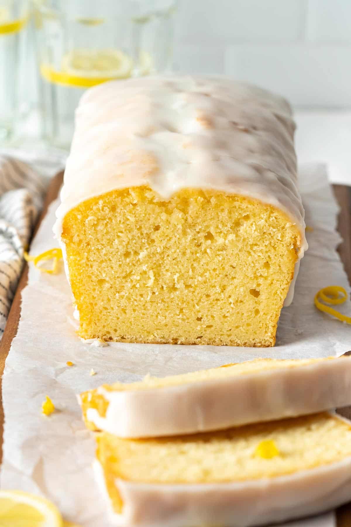 Half sliced cake loaf on a wooden cutting board.