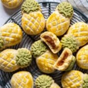 Pineapple tarts on a rack with one broken cookie on top.