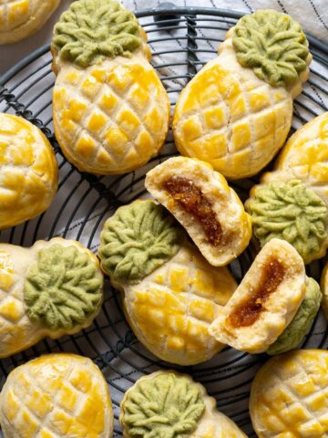 Pineapple tarts on a rack with one broken cookie on top.