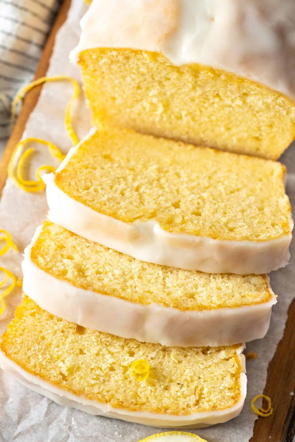 Slices of lemon loaf cake on a wooden cutting board.