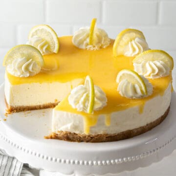 A whole no-bake lemon cheesecake with a missing portion.