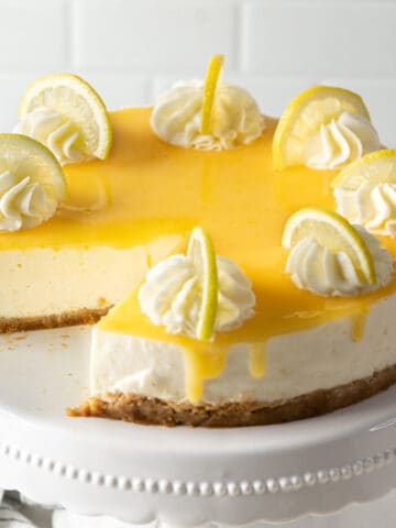 A whole no-bake lemon cheesecake with a missing portion.