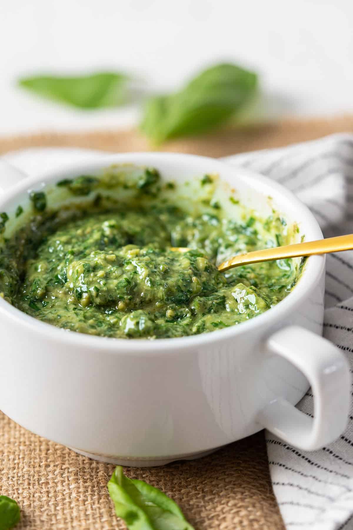 Spooning some pesto from a bowl.