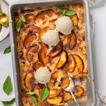 Easy peach cobbler with cake mix in a tray with ice cream.