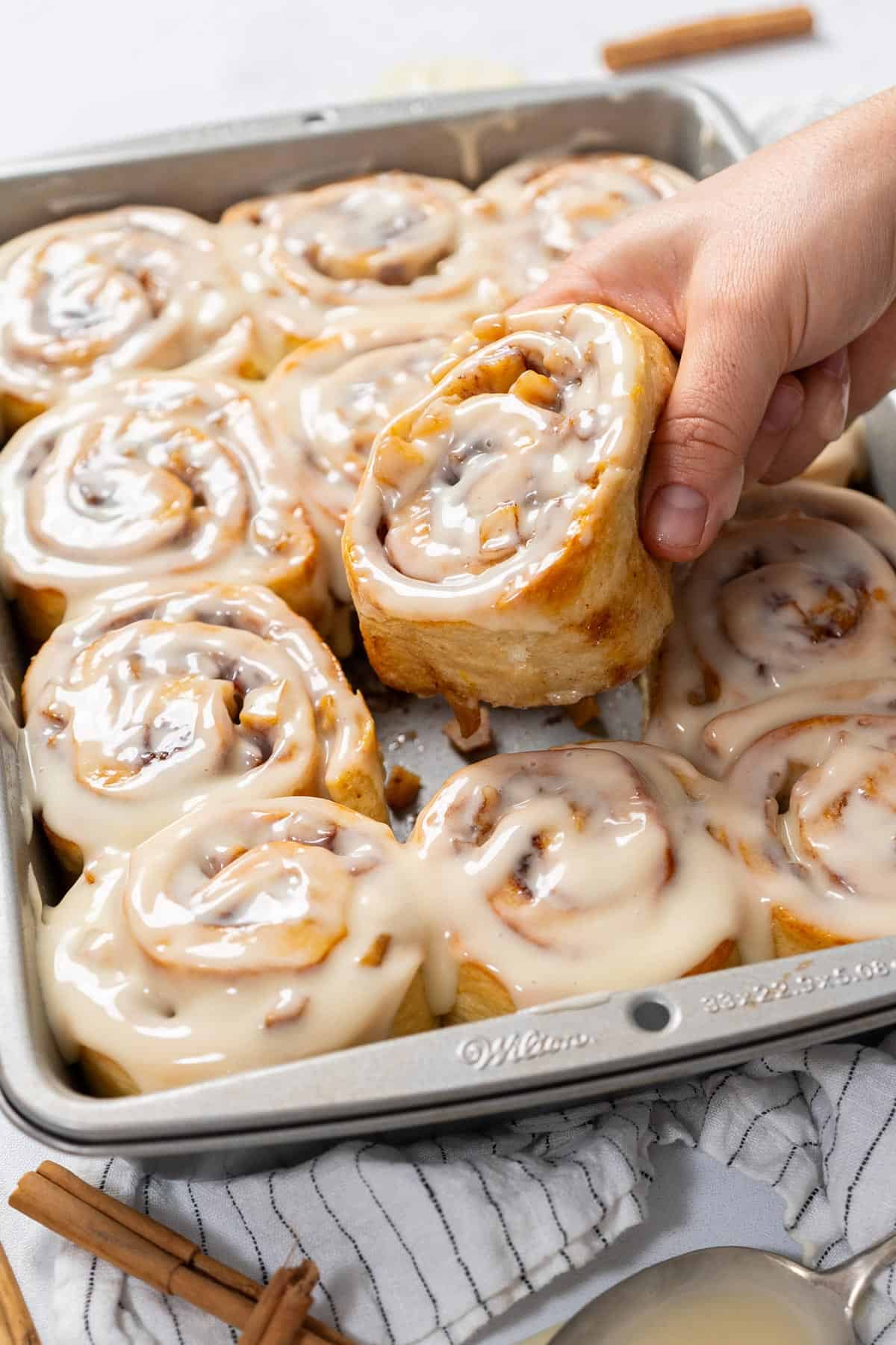 Taking out one apple cinnamon roll from the tray.