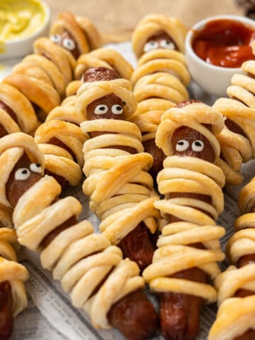 Hot dog mummies on a wooden plate.