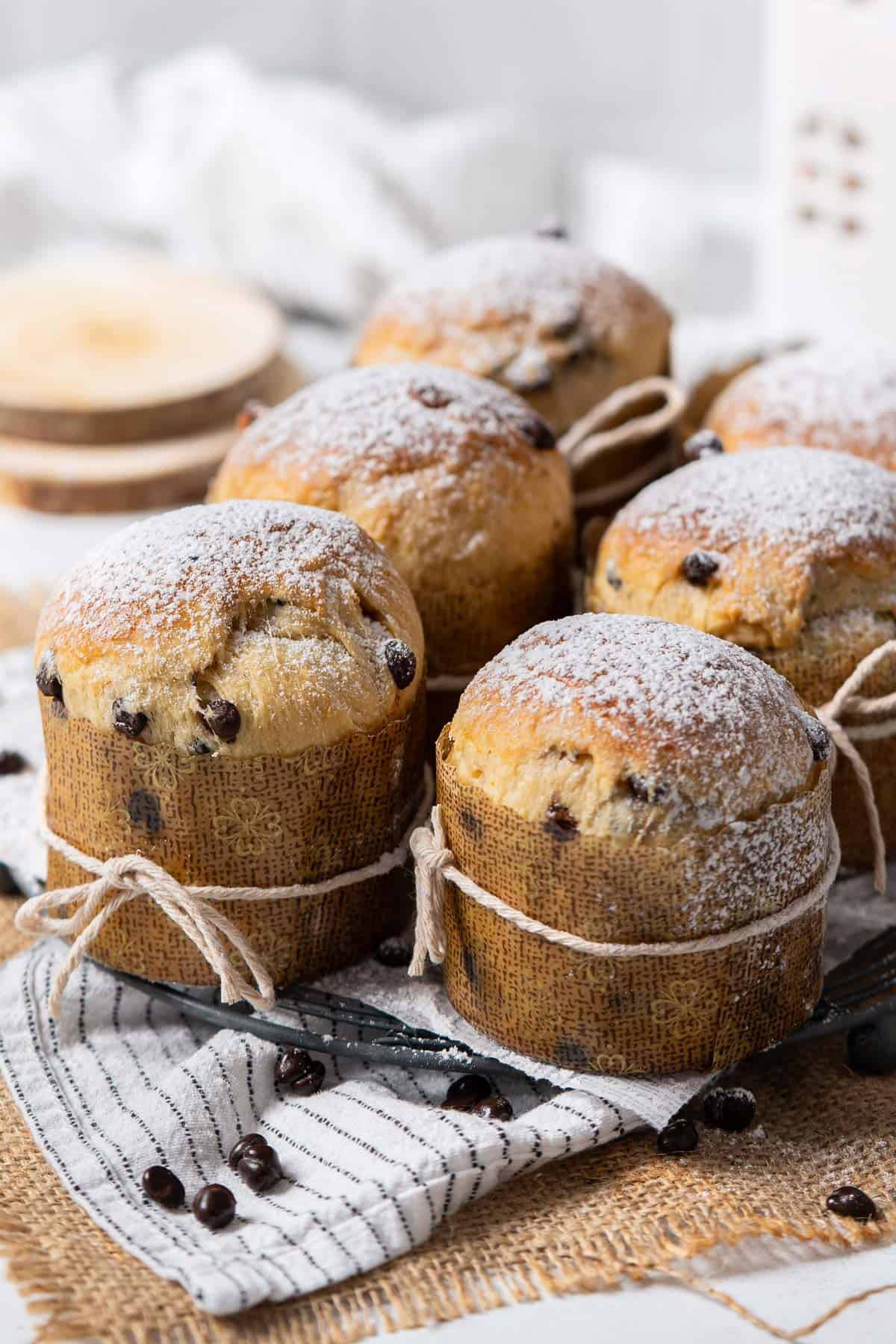 Six panettone lined up on a cooling rack.