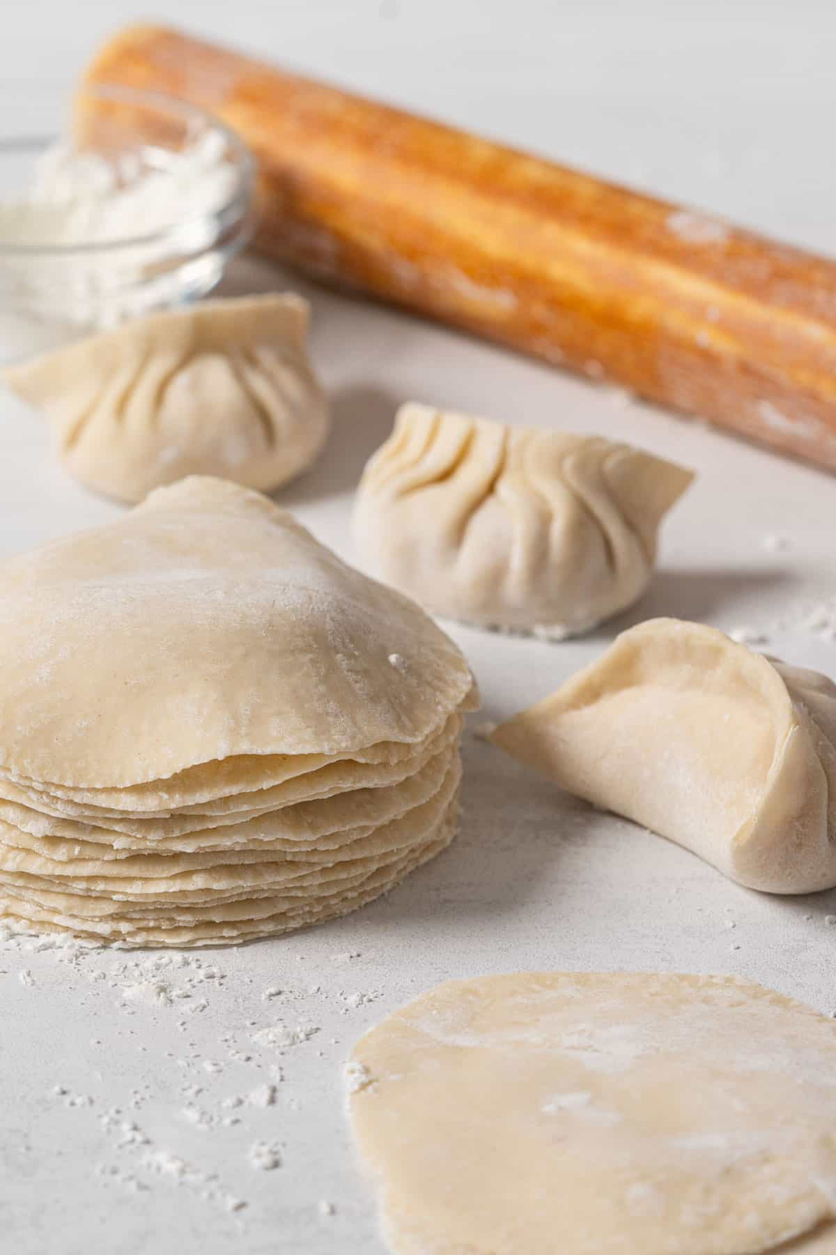 Filled dumplings and a stack of dumpling wrappers.