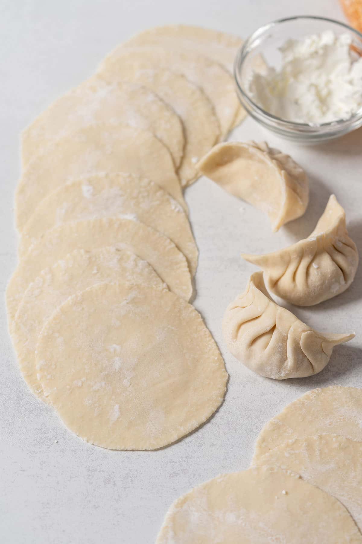 Spread out dumpling dough wrappers on a kitchen counter.