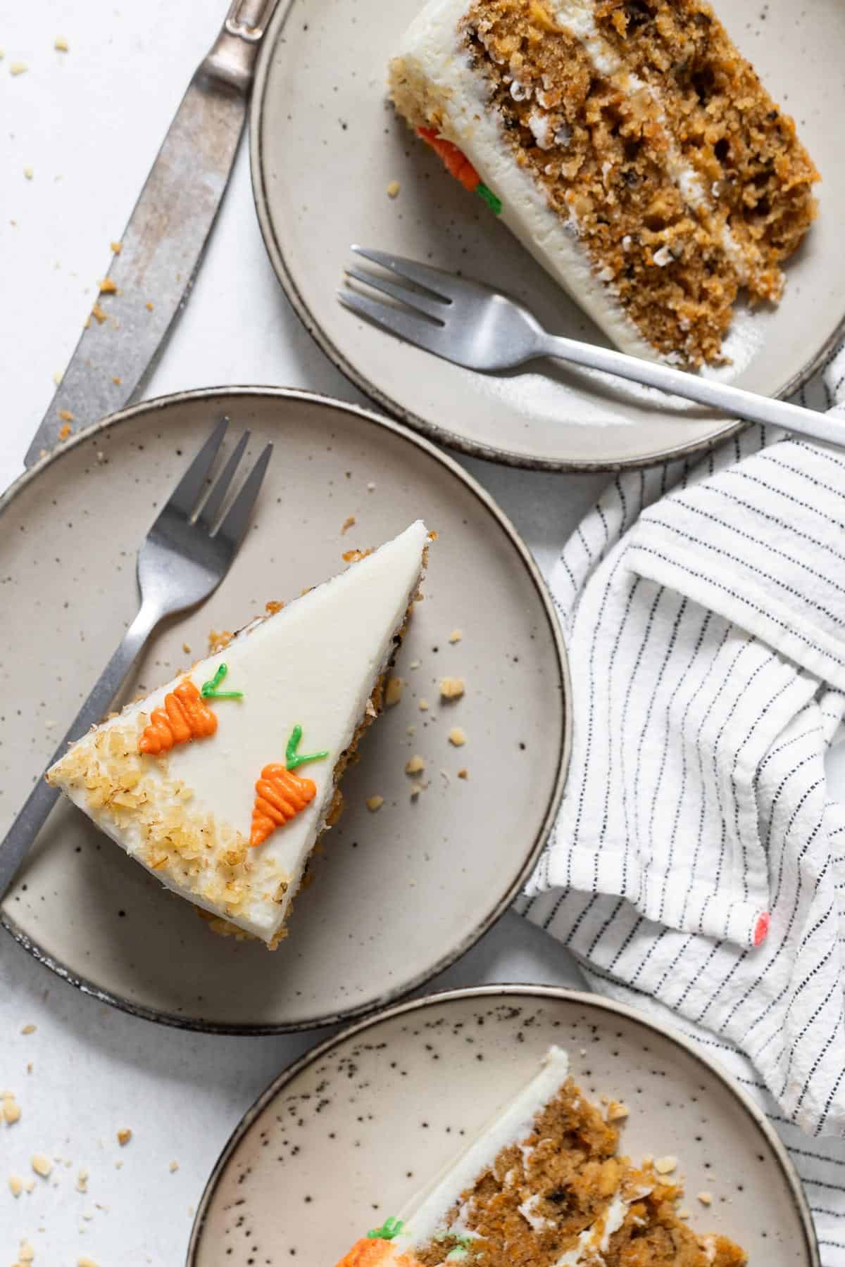 Three portions of carrot cake in plates.