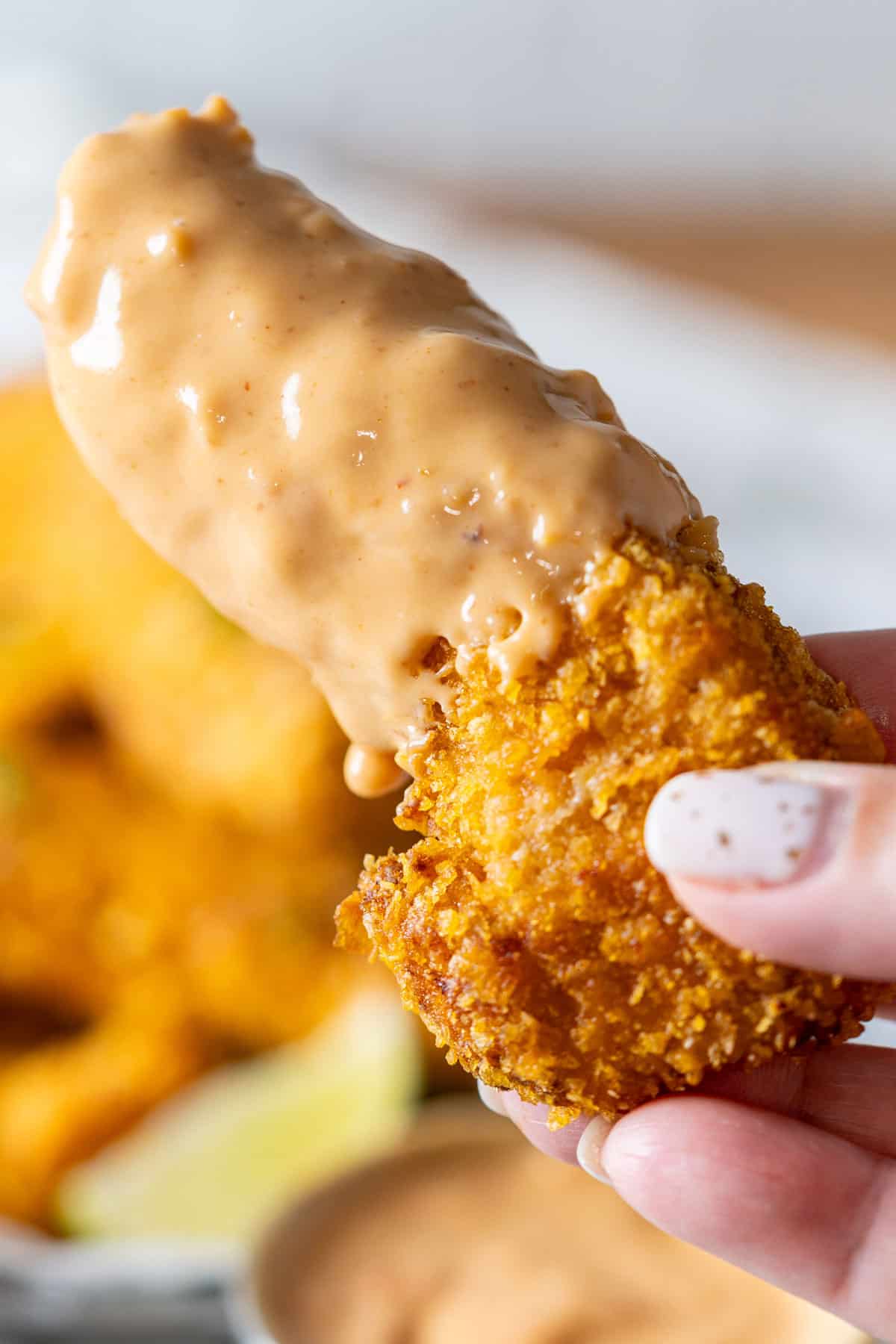 Holding a piece of Bang Bang chicken dipped in the sauce.