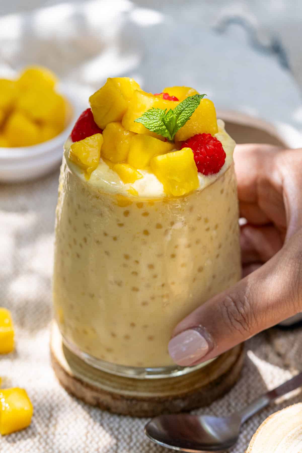 Serving mango coconut sago in a glass.