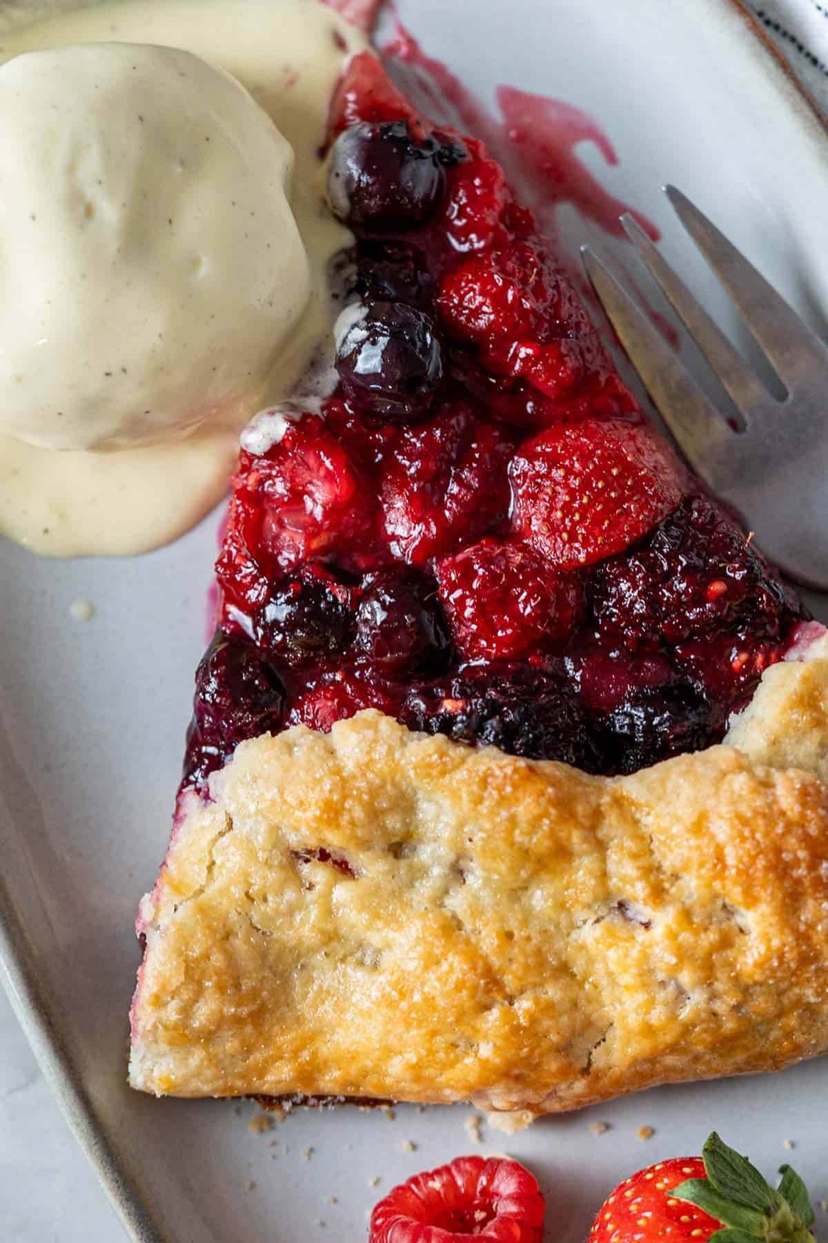 A slice of berry galette with a scoop of vanilla ice cream.