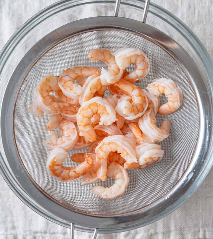 Cooked shrimp in a strainer.