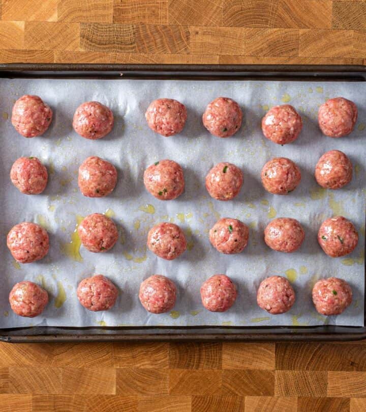 Meatball sprayed with some oil and lined on a tray.