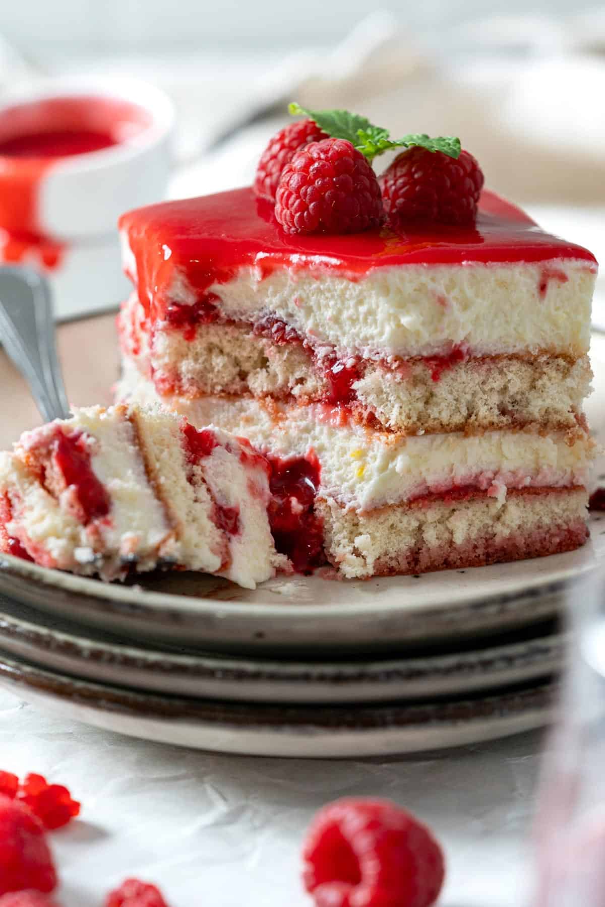 Showing the light and creamy texture of a half eaten portion of tiramisu with raspberries.