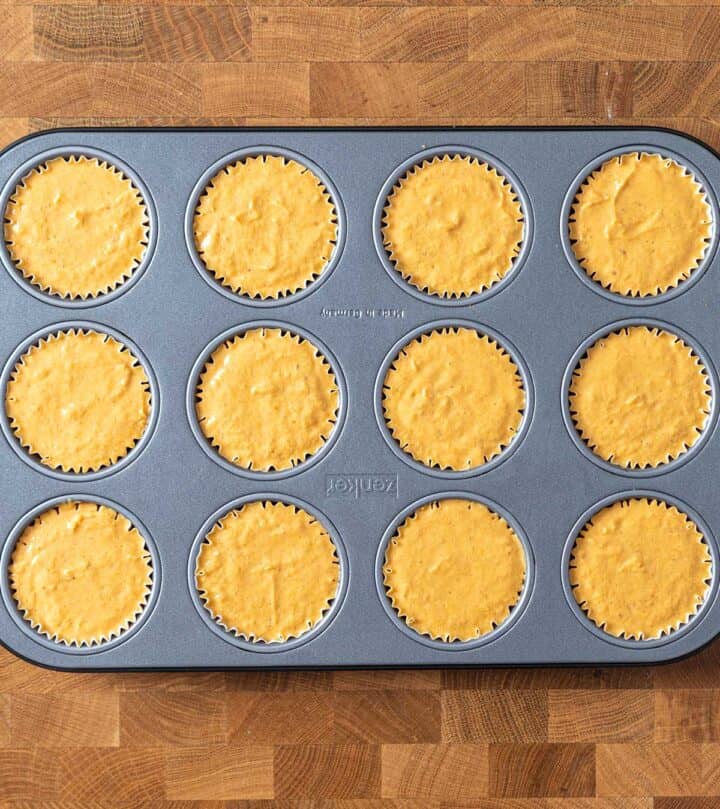 Filling muffin cups with pumpkin cheesecake batter.
