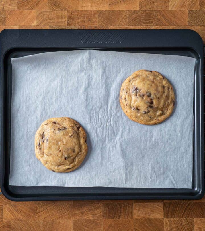 Freshly baked cookies with rippled edges and cracked tops on a tray.