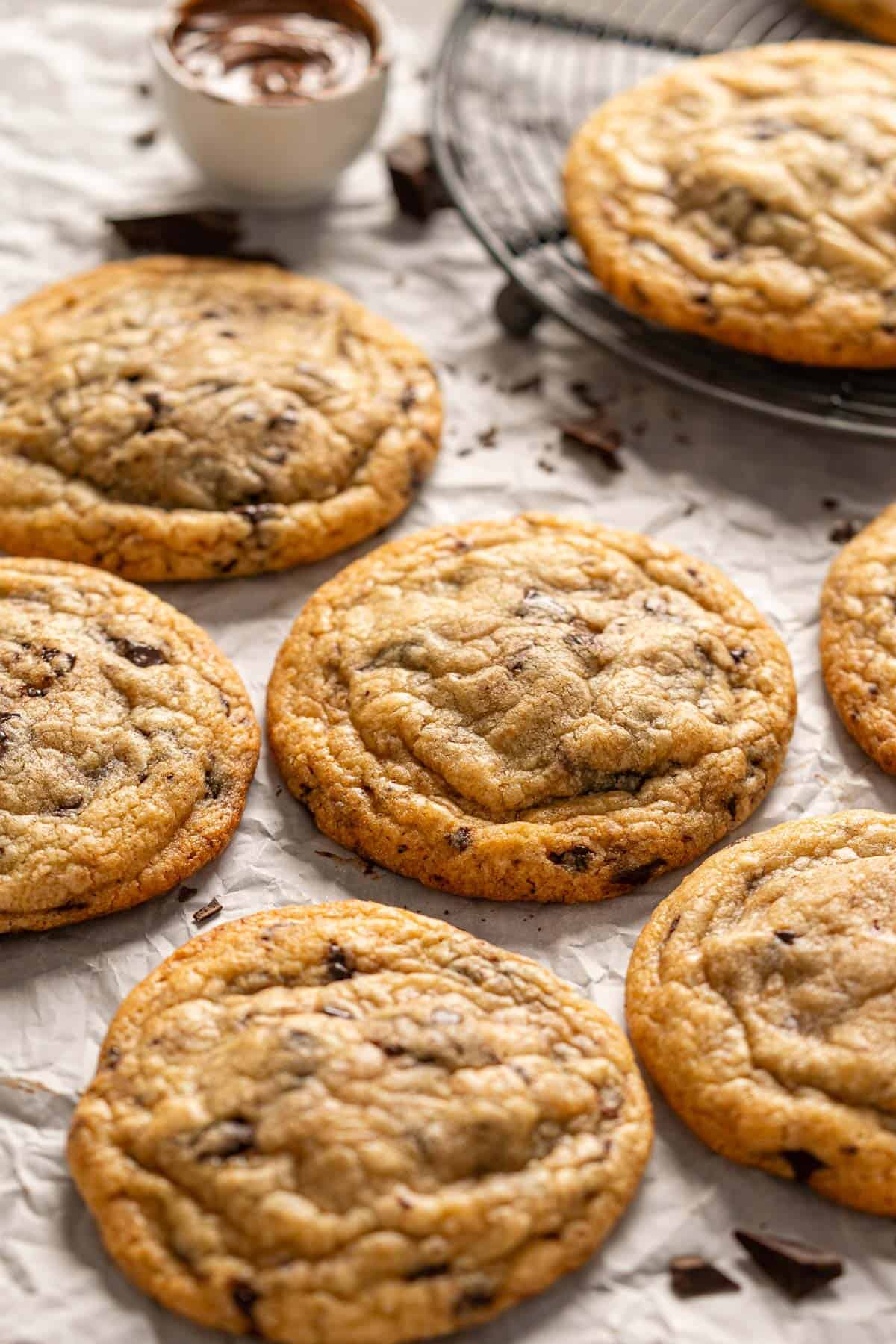 Nutella-stuffed cookies with chocolate chunks with Nutella bowl in the background.