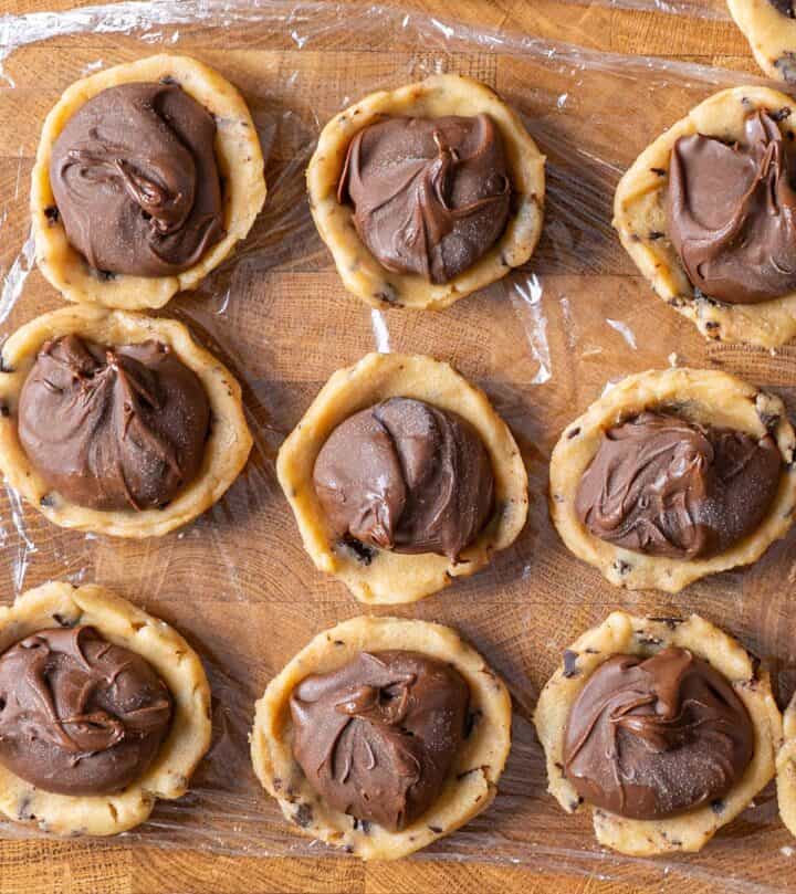 Placing a frozen Nutella disc inside the cookie dough bottom.