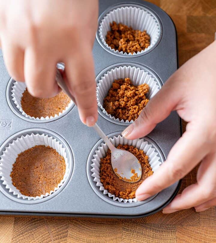 Pressing Biscoff crust into muffin pan liners.