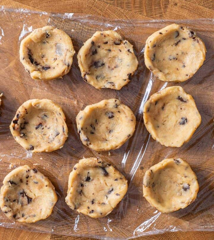 Shaping cookie dough portions into shallow bowls with thick edges.