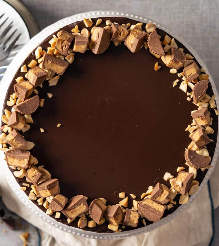 Topping no bake peanut butter chocolate cheesecake with chopped nuts and Reese's cups