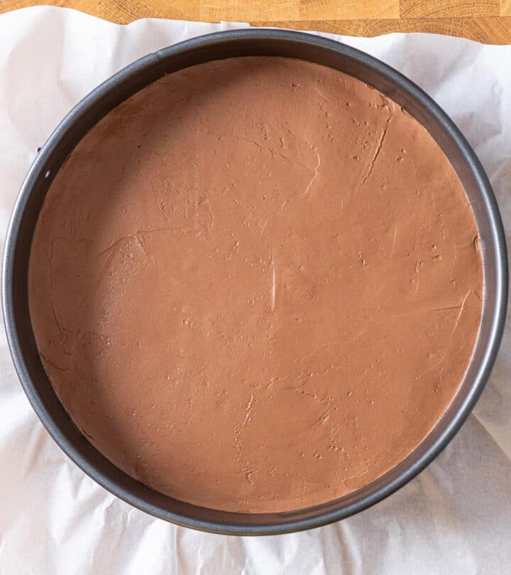 Spreading chocolate cheesecake layer evenly over crust