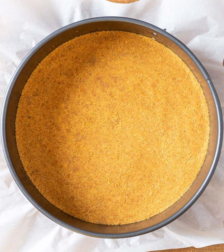 Mixing crushed biscuits with melted butter for cheesecake crust.