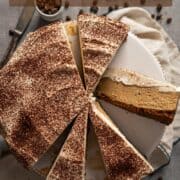 No-bake coffee cheesecake on a cake stand with some cut slices.