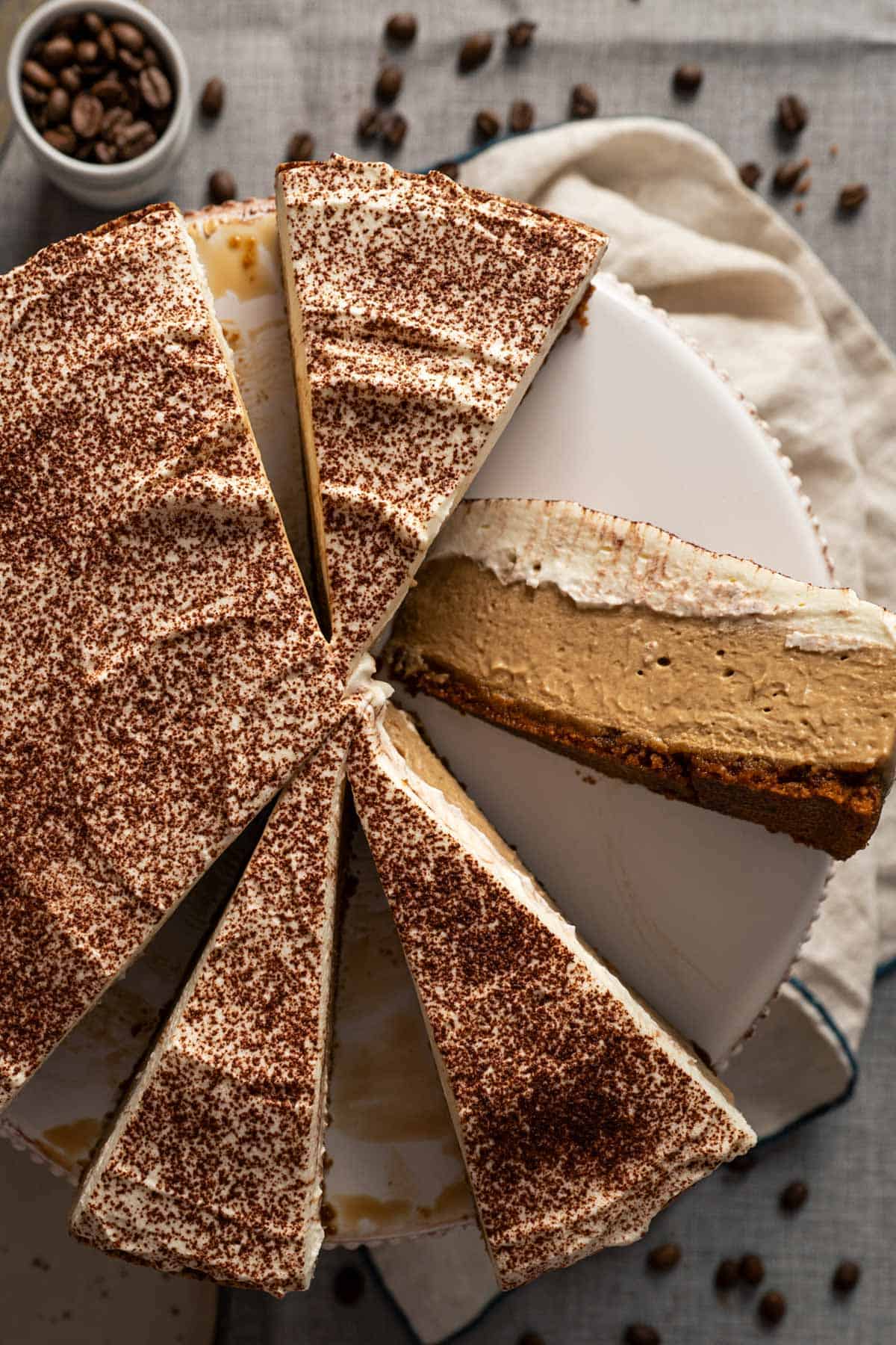 No-bake coffee cheesecake on a cake stand with some cut slices.