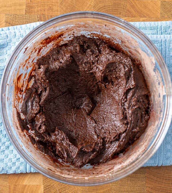 Folding flour and cocoa into chocolate mixture to form fudgy cookie dough.
