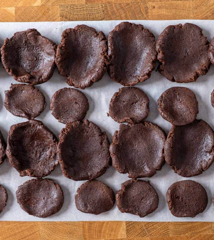 Scooping chocolate cookie dough balls, flattening base and cap for filling.