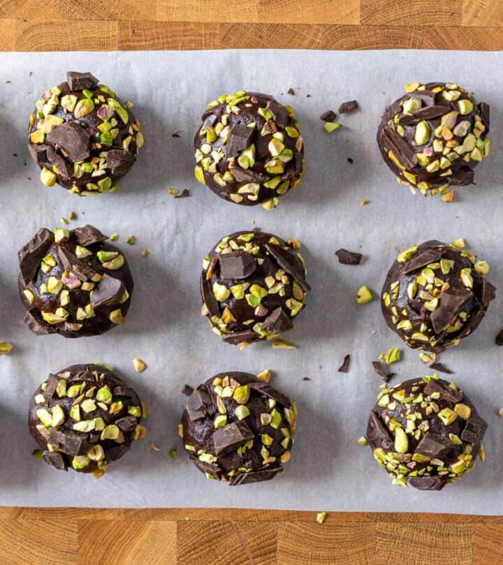 Pressing chopped pistachios and chocolate chunks on top of cookie dough.