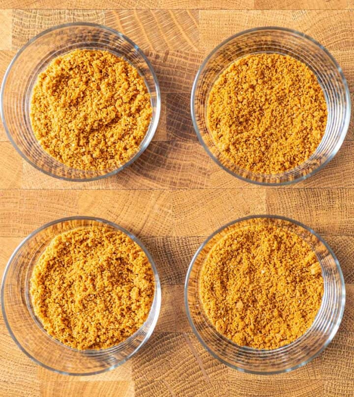 Adding crushed Biscoff cookies into the glasses.