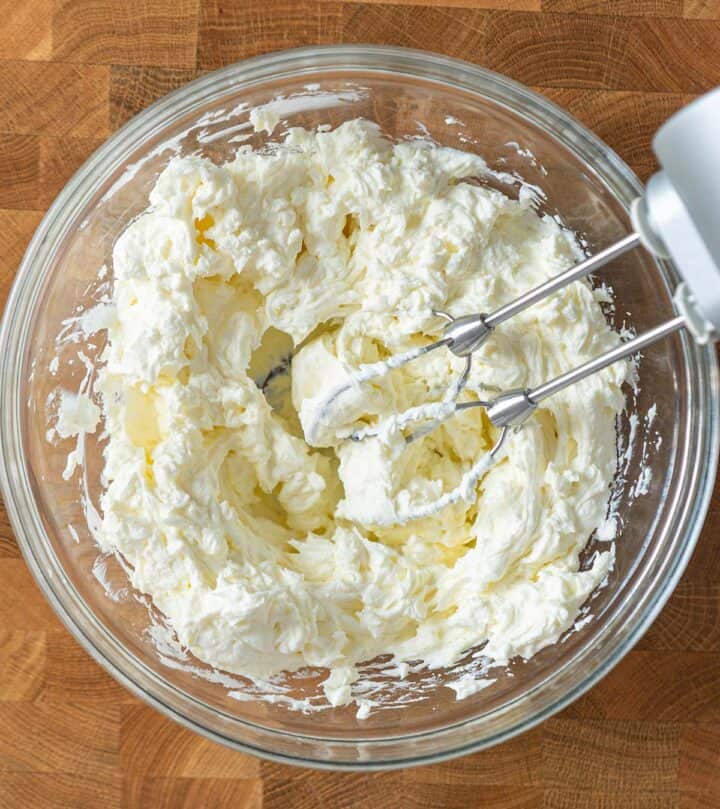 Beating full-fat cream cheese on low speed until smooth for New York cheesecake.
