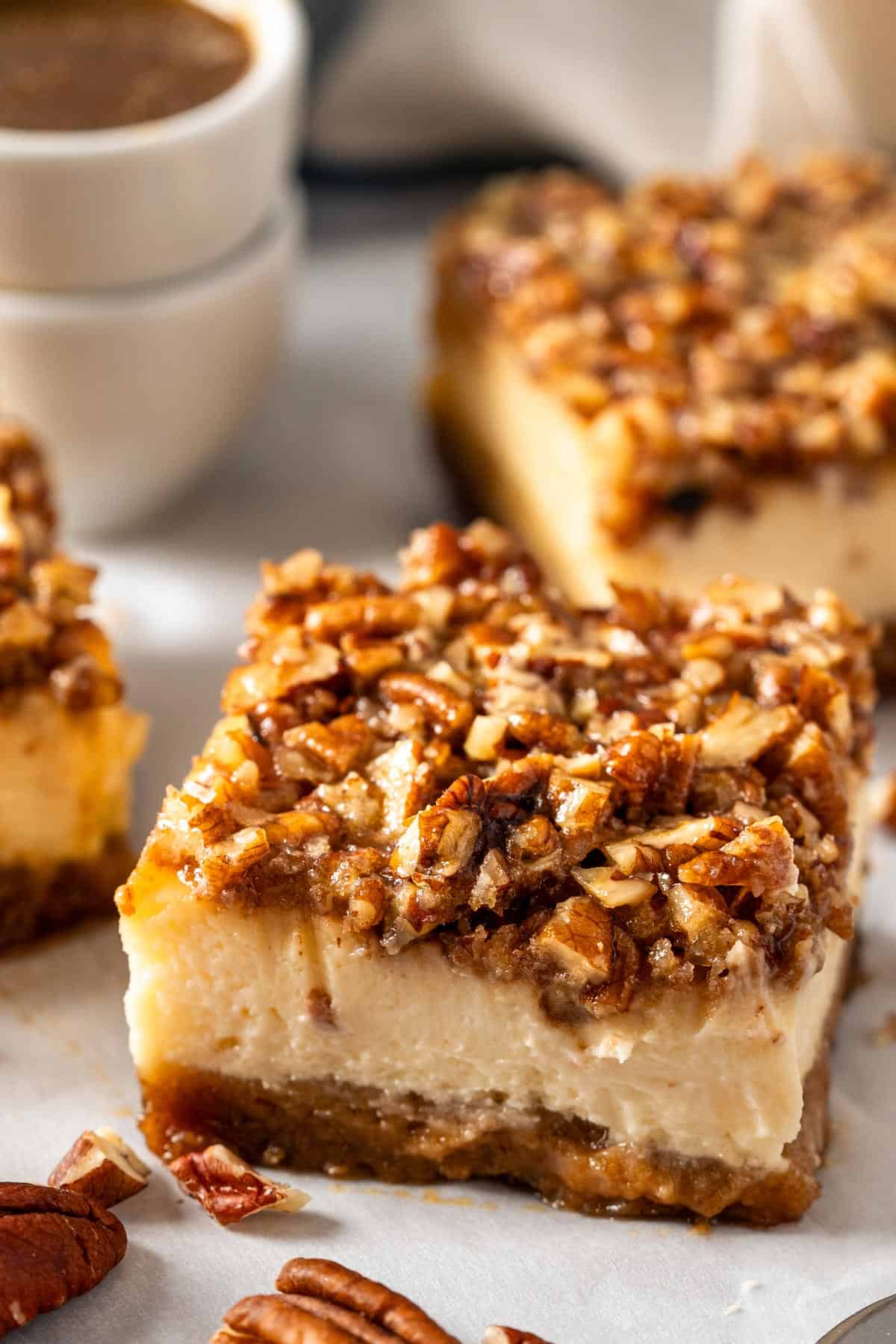 Pecan pie cheesecake bars with a bowl of sauce.