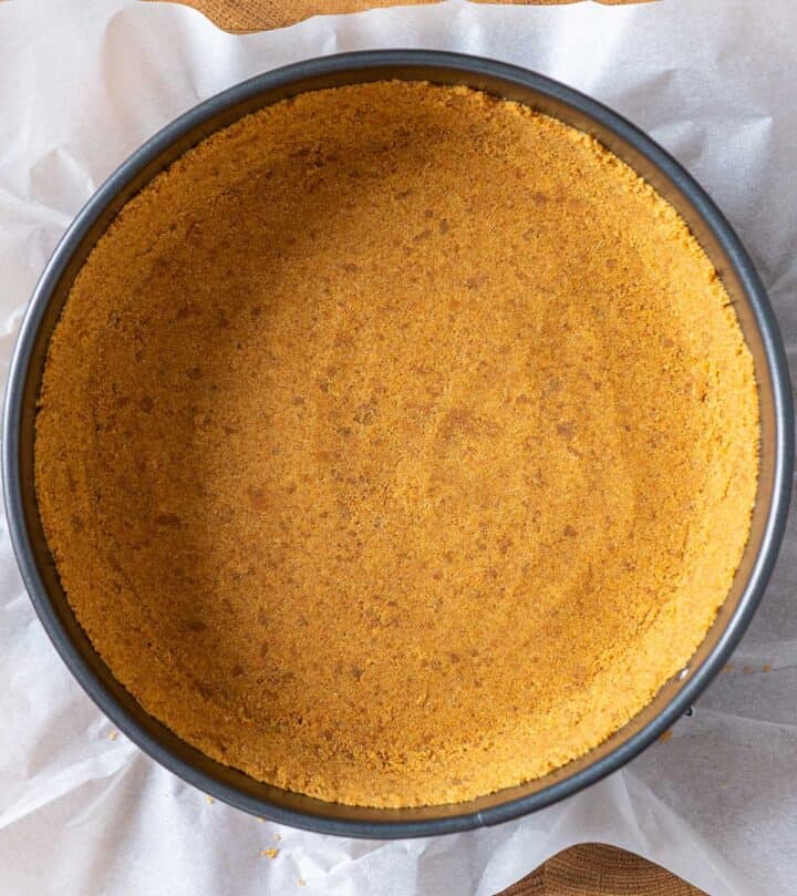 Pressing digestive biscuit (or graham) crust into a springform pan for New York cheesecake.