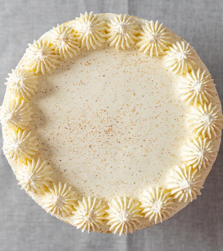 Decorating the cheesecake with whipped cream and nutmeg.