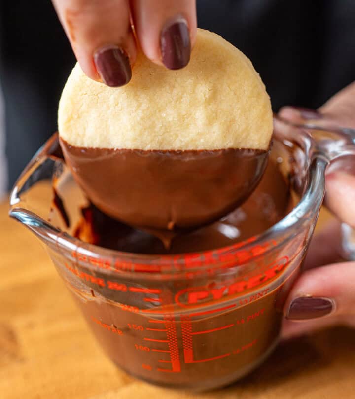 Dipping shortbread cookie in melted chocolate.