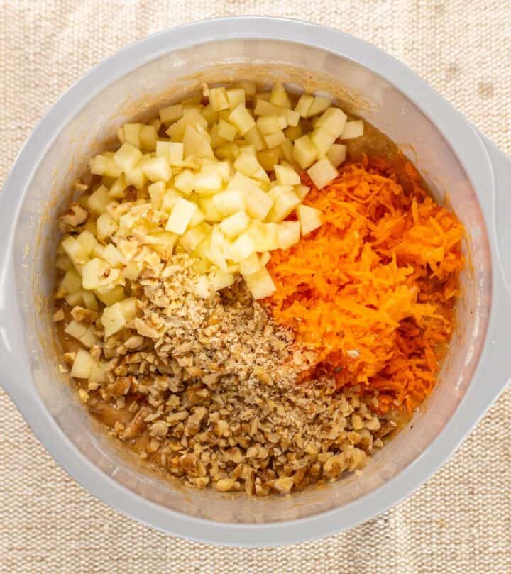 Adding carrots apple and walnuts to carrot cake batter.