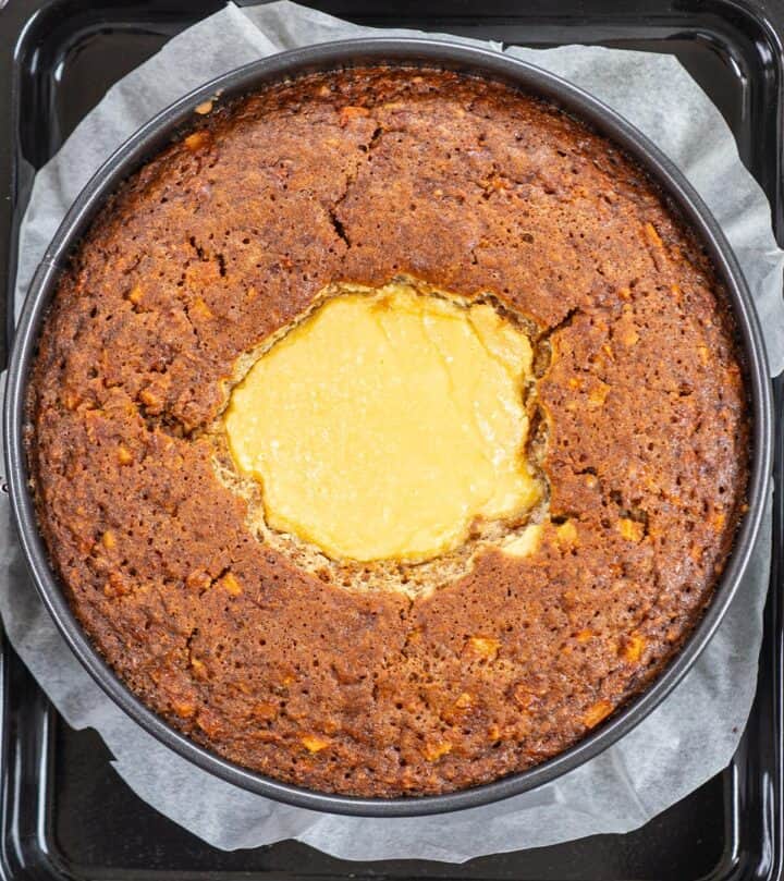 Baked carrot cake cheesecake cooling in pan.