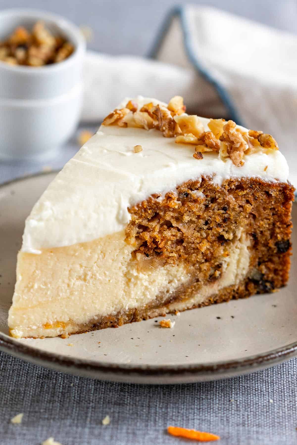 A slice of carrot cake cheesecake on a plate.