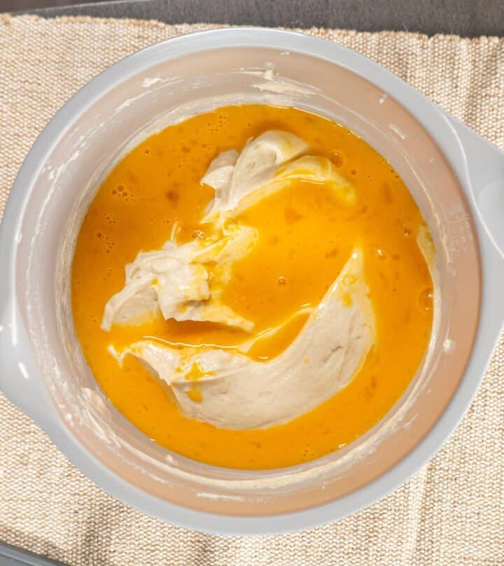 Adding eggs to cheesecake batter.