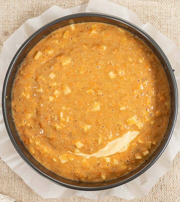 Third layer, adding remaining carrot cake layer over cheesecake batter.