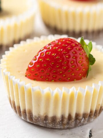 A mini cheesecake topped with half a strawberry.