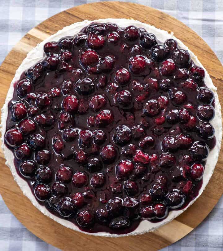 Spreading blueberry topping on top of the cheesecake.