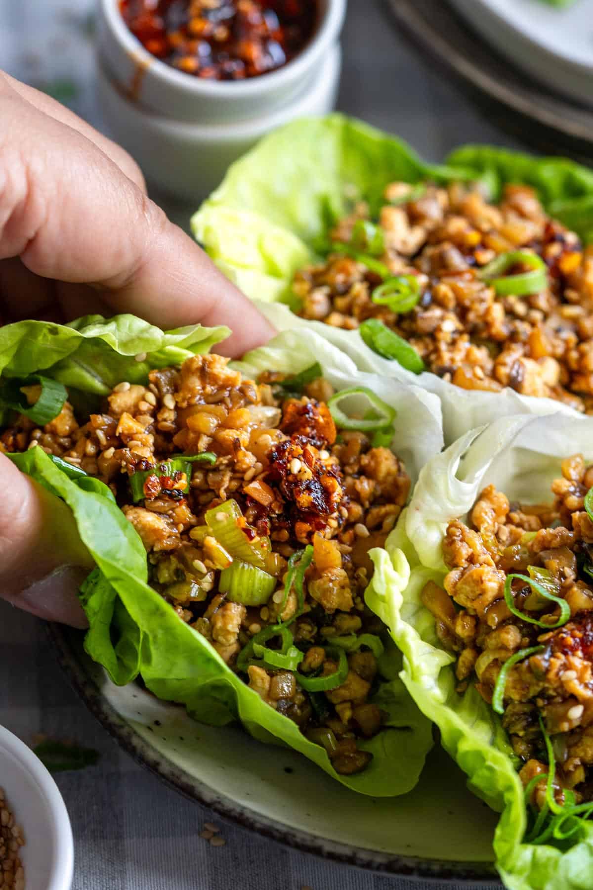 Lifting up one lettuce wrap.