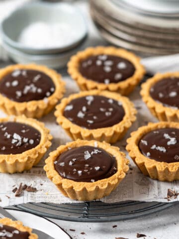 Mini chocolate tarts on a cooling rack.